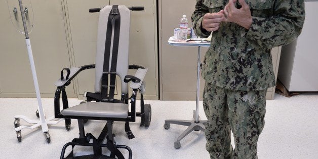 This photo reviewed by the US military and made during an escorted visit shows a US naval medic explaining the 'feeding chair' procedures at the detention facility in Guantanamo Bay, Cuba, April 9, 2014. The chair is used during the procedures of forced feeding for detainees in hunger strike. AFP PHOTO/MLADEN ANTONOV (Photo credit should read MLADEN ANTONOV/AFP/Getty Images)