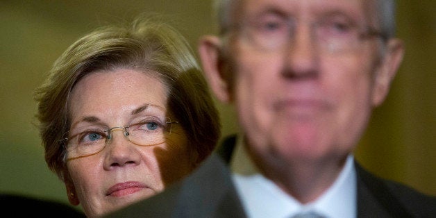 Senator Elizabeth Warren, a Democrat from Massachusetts, left, looks on as Senate Majority Leader Harry Reid, a Democrat from Nevada, speaks during a news conference following a private meeting at the U.S. Capitol Building in Washington, D.C., U.S., on Thursday, Nov. 13, 2014. U.S. Senate Democrats plan to elevate first-term Massachusetts Senator Elizabeth Warren to their leadership ranks on an expanded communications and policy committee led by third-ranking Democrat Charles Schumer. Photographer: Andrew Harrer/Bloomberg via Getty Images