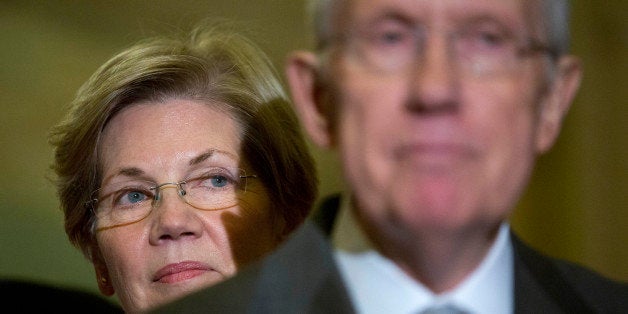 Senator Elizabeth Warren, a Democrat from Massachusetts, left, looks on as Senate Majority Leader Harry Reid, a Democrat from Nevada, speaks during a news conference following a private meeting at the U.S. Capitol Building in Washington, D.C., U.S., on Thursday, Nov. 13, 2014. U.S. Senate Democrats plan to elevate first-term Massachusetts Senator Elizabeth Warren to their leadership ranks on an expanded communications and policy committee led by third-ranking Democrat Charles Schumer. Photographer: Andrew Harrer/Bloomberg via Getty Images 