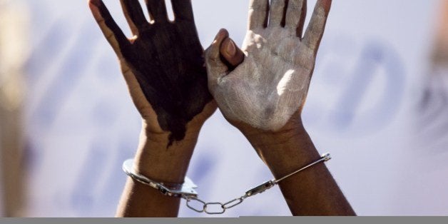 An African asylum seeker, who entered Israel illegally via Egypt, uses handcuffs and raises up his hands painted in black and white during a protest in front of the Israeli Interior Ministry in the Mediterranean coastal city of Tel Aviv on February 11, 2014, after several days of mass protests against Israel's immigration policies. The migrants, primarily from Eritrea and Sudan, marched from downtown Tel Aviv to the embassies, calling for help in the face of Israel's refusal to give them refugee status and its detention without trial of hundreds of asylum seekers. AFP PHOTO / JACK GUEZ (Photo credit should read JACK GUEZ/AFP/Getty Images)