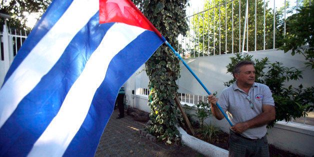 A man waves a Cuban flag while celebrating the restoration of diplomatic relations between the island nation and the United States, in the courtyard of the Cuban Embassy in Santiago, Chile, Wednesday Dec. 17, 2014. After a half-century of Cold War acrimony, the United States and Cuba abruptly moved on Wednesday to restore diplomatic relations between the two nations. U.S. President Barack Obama spoke as Cuban President Raul Castro was addressing his nation in Havana, where church bells rang and school teachers paused lessons to mark the news. (AP Photo/Luis Hidalgo)