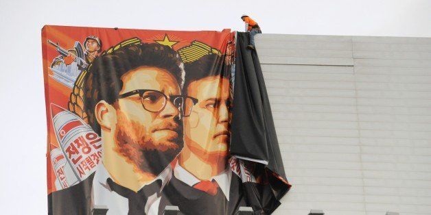 Workers remove a poster-banner for 'The Interview' from a billboard in Hollywood, California, December 18, 2014 a day after Sony announced was cancelling the movie's Christmas release due to a terrorist threat. Sony defended itself Thursday against a flood of criticism for canceling the movie which angered North Korea and triggered a massive cyber-attack, as the crisis took a wider diplomatic turn. AFP PHOTO / MICHAEL THURSTON (Photo credit should read Michael THURSTON/AFP/Getty Images)