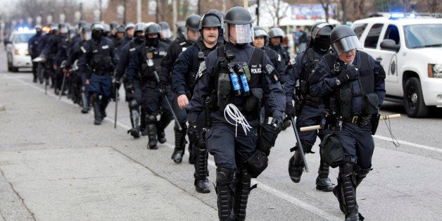 Police wearing riot gear walk past Edward Jones Dome following an NFL football game between the St. Louis Rams and the Oakland Raiders, Sunday, Nov. 30, 2014, in St. Louis. Police and protesters clashed after the game as protests continue following a grand jury's decision not to indict a Ferguson police officer in the shooting death of Michael Brown. (AP Photo/Tom Gannam)