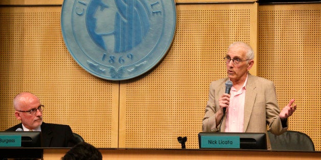 Seattle City Council member Nick Licata, right, speaks next to the seal of the City of Seattle as Council president Tim Burgess, left, looks on, Monday, June 2, 2014, during debate before the Council passed a$15 minimum wage measure. (AP Photo/Ted S. Warren)