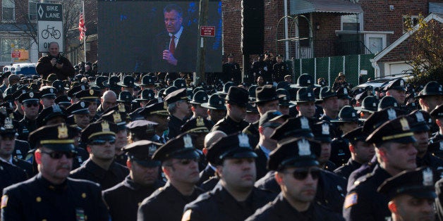 Police officers turn their backs as New York City Mayor Bill de Blasio speaks at the funeral of New York city police officer Rafael Ramos in the Glendale section of Queens, Saturday, Dec. 27, 2014, in New York. Ramos and his partner, officer Wenjian Liu, were killed Dec. 20 as they sat in their patrol car on a Brooklyn street. The shooter, Ismaaiyl Brinsley, later killed himself. (AP Photo/John Minchillo)