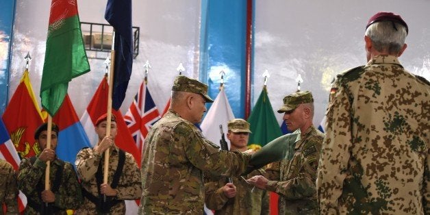 US General John Campbell (C) folds the flag of the NATO-led International Security Assistance Force (ISAF) during a ceremony marking the end of ISAF's combat mission in Afghanistan at ISAF headquarters in Kabul on December 28, 2014. NATO formally ended its war in Afghanistan on December 28, holding a low-key ceremony in Kabul after 13 years of conflict that have left the country in the grip of worsening insurgent violence.The event was arranged in secret due to the threat of Taliban strikes in the Afghan capital, which has been hit by repeated suicide bombings and gun attacks over recent years. 'Together... we have lifted the Afghan people out of the darkness of despair and given them hope for the future,' NATO commander US General John Campbell told assembled soldiers. 'You've made Afghanistan stronger and our countries safer.' On January 1, the US-led International Security Assistance Force (ISAF) combat mission, which has suffered 3,485 military deaths since 2001, will be replaced by a NATO 'training and support' mission. AFP PHOTO / SHAH Marai (Photo credit should read SHAH MARAI/AFP/Getty Images)