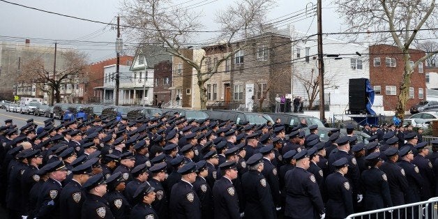 New York Police Department (NYPD) officers pay their respect as the procession of NYPD officer Wenjian Liu passes by in New York's borough of Brooklyn on January 4, 2015. A sea of blue uniformed officers crowded around a Brooklyn funeral home to honor Wenjian Liu, 32, shot in the head with partner Rafael Ramos, 40, on December 20, 2014 as the pair sat in their patrol car. The brutal double-slaying at the hands of a black gunman claiming to be avenging the deaths of African-Americans during confrontations with police shocked the nation's largest city. AFP PHOTO/JEWEL SAMAD (Photo credit should read JEWEL SAMAD/AFP/Getty Images)