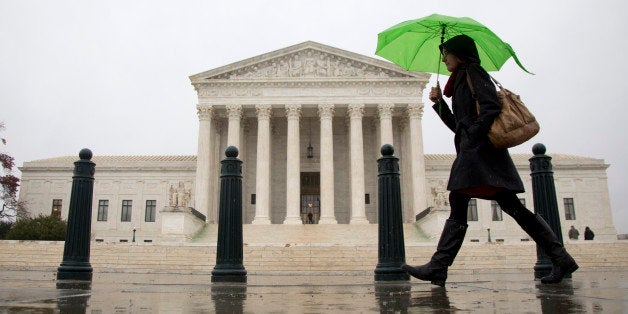 As a steady rain falls, a morning commuter make her way past the Supreme Court in Washington, Tuesday,...