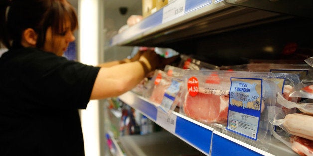 Rashers of Tesco Plc own brand bacon sit in a refrigerated meat cabinet as an employee arranges meat products inside the Comm