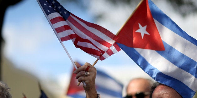 MIAMI, FL - DECEMBER 20: A protester holds an American flag and a Cuban one as she joins with others opposed to U.S. President Barack Obama's announcement earlier in the week of a change to the United States Cuba policy stand together at Jose Marti park on December 20, 2014 in Miami, Florida. President Obama announced a move toward normalizing the relationship with Cuba after a swap of prisoners took place. (Photo by Joe Raedle/Getty Images)