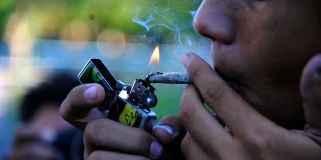 A young man smokes marijuana during a demo for its legalization in front the National congress building in Asuncion, Paraguay, on December 20, 2014 AFP PHOTO / Norberto DUARTE (Photo credit should read NORBERTO DUARTE/AFP/Getty Images)