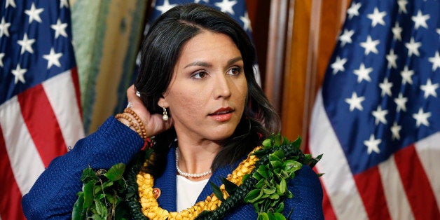 Rep. Tulsi Gabbard, D-Hawaii, waits for a photo with Speaker of the House John Boehner, R-Ohio, in the Rayburn Room of the Capitol after the new 113th Congress convened on Thursday, Jan. 3, 2013, in Washington. The official oath of office for all members of the House was administered earlier in the House chamber. (AP Photo/J. Scott Applewhite)