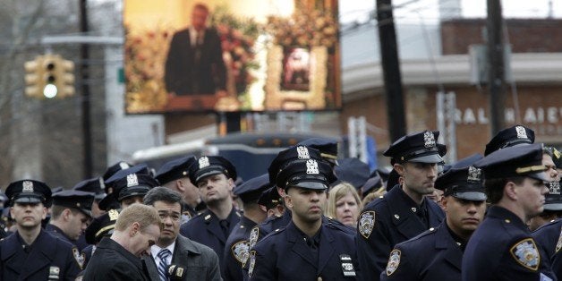 Some police officers turn their back to a large screen that displays New York City Mayor Bill de Blasio speaking during the funeral of Officer Wenjian Liu in the Brooklyn borough of New York, Sunday, Jan. 4, 2015. Liu and his partner, officer Rafael Ramos, were killed Dec. 20 as they sat in their patrol car on a Brooklyn street. The shooter, Ismaaiyl Brinsley, later killed himself. (AP Photo/Seth Wenig)