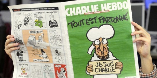 A man reads, in a newsroom in Paris, the last issue of French satirical weekly Charlie on January 13, 2015. A defiant Charlie