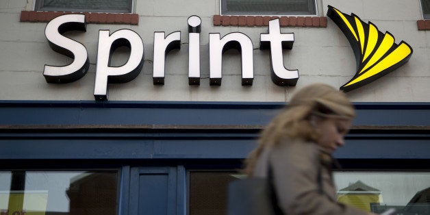 A pedestrian uses a mobile device while walking past a Sprint Corp. store in Washington, D.C., U.S., on Friday, Oct. 24, 2014