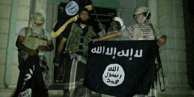 A picture taken with a mobile phone early on May 24, 2014 shows Al-Qaeda militants posing with Al-Qaeda flags in front of a museum in Seiyun, second Yemeni city of Hadramawt province, after launching a massive pre-dawn assault that killed at least 15 soldiers and police. The assault in Hadramawt, a jihadist stronghold that has seen large-scale attacks on the army in the past, came as troops pressed a month-old ground offensive against Al-Qaeda in Abyan and Shabwa provinces to the west. AFP PHOTO / STR (Photo credit should read -/AFP/Getty Images)