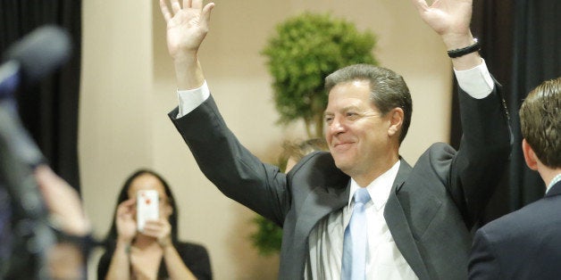 Kansas Gov. Sam Brownback emerges to a cheering crowd in Topeka , Kan., on Tuesday, Nov. 4, 2014, after he was re-elected. (T