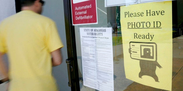 FILE - In this May 5, 2014 file photo, a voter walks past a "Please Have Photo ID Ready" sign as he enters an early-voting po