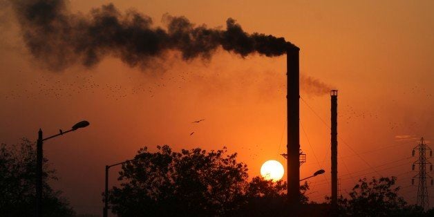 Birds fly past at sun set as smoke emits from a chimney at a factory in Ahmadabad, India, Monday, Dec. 8, 2014. The momentum
