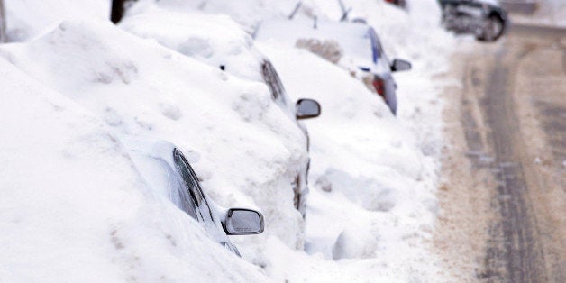 A line of cars sit buried in snow banks in Somerville, Mass., Tuesday, Feb. 10, 2015. The latest snowstorm left the Boston area with another two feet of snow and forced the MBTA to suspend all rail service for the day. (AP Photo/Josh Reynolds)