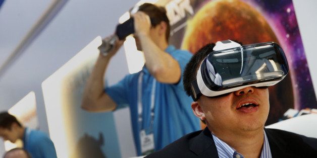 An attendee tries on a Samsung Electronics Co. Gear VR headset during the 2015 Consumer Electronics Show (CES) in Las Vegas, Nevada, U.S., on Tuesday, Jan. 6, 2015. This year's CES will be packed with a wide array of gadgets such as drones, connected cars, a range of smart home technology designed to make everyday life more convenient and quantum dot televisions, which promise better color and lower electricity use in giant screens. Photographer: Patrick T. Fallon/Bloomberg via Getty Images