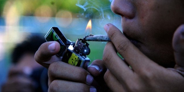 A young man smokes marijuana during a demo for its legalization in front the National congress building in Asuncion, Paraguay