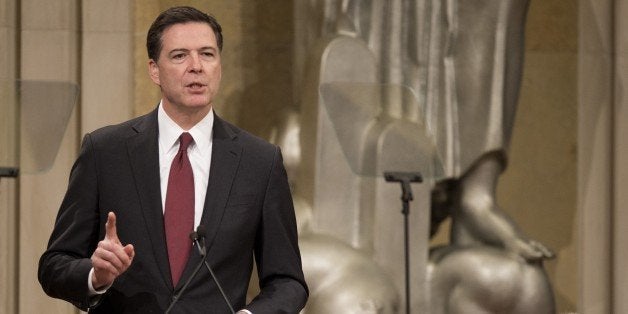 Director of the Federal Bureau of Investigation (FBI) James Comey (L) speaks accompanied by US Attorney General Eric Holder (R) during an event for National Slavery and Human Trafficking Prevention Month at the Justice Department in Washington, DC, January 29, 2015. AFP PHOTO/JIM WATSON (Photo credit should read JIM WATSON/AFP/Getty Images)