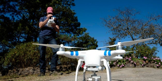 A man with a camera equipped radio controlled quadcopter drone 