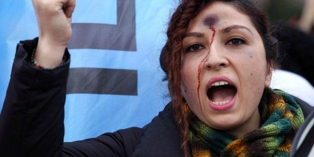 A woman with a bullet hole painted on her forehead takes part in a demonstration against the murder of 20-year-old Ozgecan A