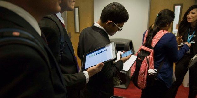 Students view mobile devices while waiting to speak to a representative at the International Business Machine Corp. (IBM) booth during an engineering and technology career fair at the New York University (NYU) Polytechnic School of Engineering in the Brooklyn borough of New York, U.S., on Thursday, Feb. 12, 2015. Applications for unemployment benefits climbed last week to a level thats consistent with progress in the U.S. labor market. Photographer: Michael Nagle/Bloomberg via Getty Images