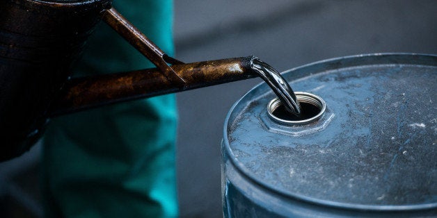 FILE PHOTO: A worker pours liquid oil into a barrel at the delayed coker unit of the Duna oil refinery operated by MOL Hungar