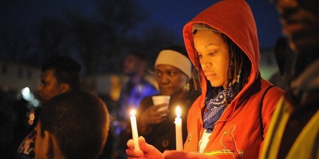 A woman holds a candle while protesters demonstrate against racism in the 'Reclaim MLK' march January...