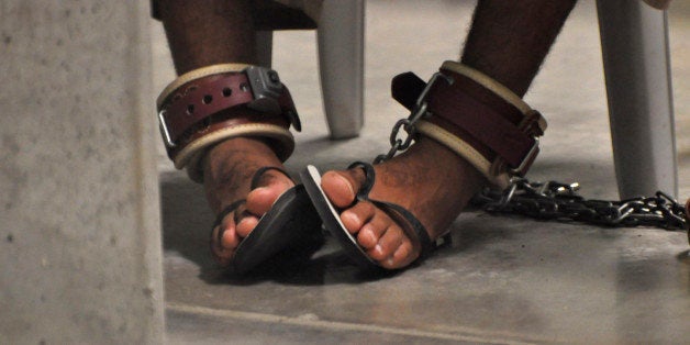 In this photo, reviewed by a US Department of Defense official, a Guantanamo detainee's feet are shackled to the floor as he