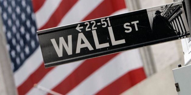 The flags on the facade of the New York Stock Exchange are a backdrop for a Wall Street street sign, Thursday morning, Aug. 1