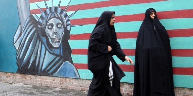 Iranian women walk past the painted wall of the former US embassy on November 4, 2014 in Tehran where takes place a demonstra