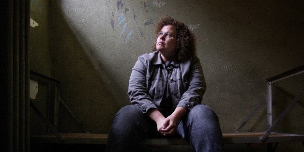 Woman sitting and looking up light is shining into the cell from a high window.