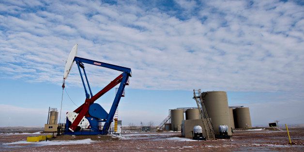 A pumpjack stands near storage containers on the site of an oil well outside Williston, North Dakota, U.S., on Thursday, Feb. 12, 2015. A plunge in global energy prices that has put some North Dakota oil rigs in a deep freeze has yet to chill the state's hiring climate. Photographer: Daniel Acker/Bloomberg via Getty Images