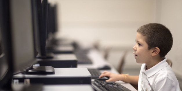 Six year old boy learns the keyboard during a computer class.