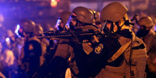 FILE - In this Aug. 17, 2014, file photo, police advance after tear gas was used to disperse a crowd during a protest for Michael Brown, who was killed by a police officer in Ferguson, Mo. Brown's shooting has prompted a flurry of legislation in his home state, where politicians are proposing to curb police tactics, prosecutorial powers and even traffic fines in an attempt to address concerns that have fueled nationwide protests. (AP Photo/Charlie Riedel, File)