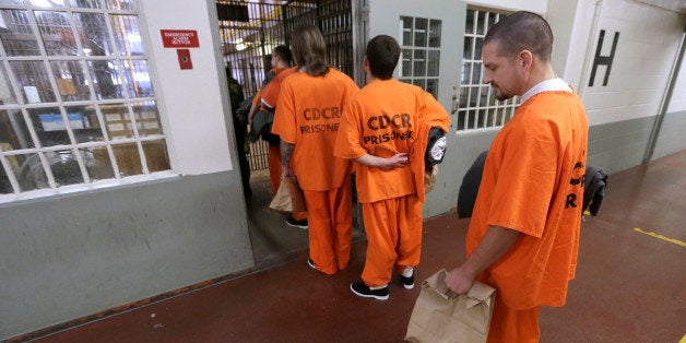 In this photo taken Thursday, Feb. 20, 2014, carrying his belongings and blanket Derek Martinez, 37, waits to enter a his assigned cell block after his arrival at the Deuel Vocational Institution in Tracy Calif. Martinez, a second strike offender from Shasta County, has been serving a life term with the possibility of parole for first degree murder since 2007. California counties are thwarting the state's efforts to comply with a federal court order to reduce it's inmate population by sending state prisons far more convicts than anticipated including a record number of second-strikers. The state is trying to comply with a landmark restructuring of its criminal justice system through a nearly 3-year-old law pushed by Gov. Jerry Brown that keeps lower-level felons in county jails while reserving scarce state prison cells for serious, violent and sexual offenders.(AP Photo/Rich Pedroncelli)