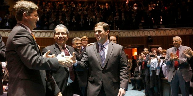 Arizona Gov. Doug Ducey, middle, shakes hands with Phoenix Mayor Greg Stanton, left, as Roberto Rodriguez Hernandez, second from left, Mexico's Consul General in Arizona, looks on, as Ducey arrives on the House floor to give his state-of-the-state address at the Arizona Capitol, Monday, Jan. 12, 2015, in Phoenix. (AP Photo/Ross D. Franklin)