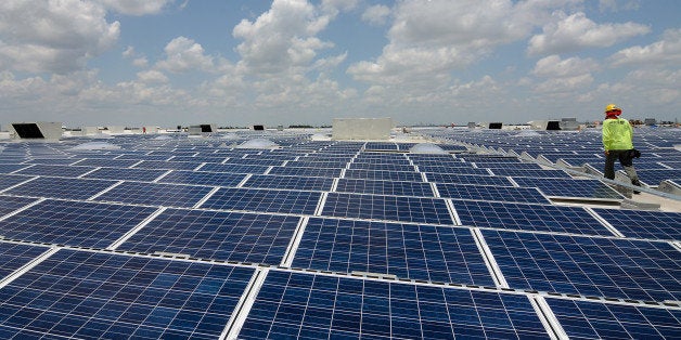 A contractor walks past solar panels on the roof of a new IKEA store in Miami, Florida, U.S., on Tuesday, May 20, 2014. IKEA US is currently the second largest private commercial user and owner of solar panels and is in the midst of investing $150 million in Photovoltaic systems, according to the company web site. Photographer: Christina Mendenhall/Bloomberg via Getty Images