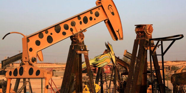 Old oil pumps, including one painted like a giraffe and another like a bird, stand in a scrap yard in the desert oil fields o