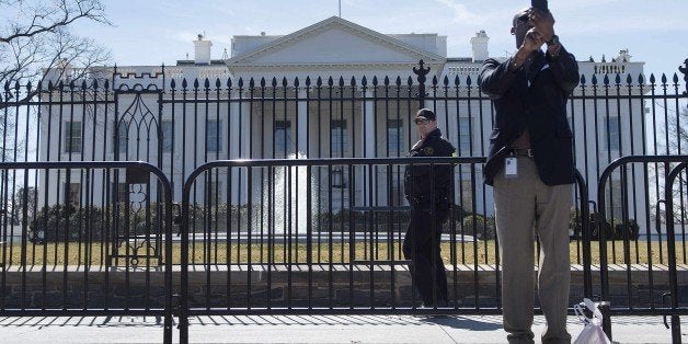 An uniformed US Secret Service officer (C) patrols Pennsylvania Avenue in front of the White House in Washington, DC, March 1