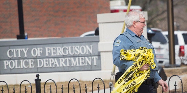 FERGUSON, MO - MARCH 12: A police officer removes crime scene tape from outside the police station following an investigation of the area after two officers were shot and wounded during last night's protest on March 12, 2015 in Ferguson, Missouri. Demonstrators had gathered outside the station to celebrate and protest after learning the city's police chief would be stepping down following the release of a Justice Department report that disparaged the department. Ferguson has faced many violent protests since the August shooting death of Michael Brown by a Ferguson police officer. (Photo by Scott Olson/Getty Images)