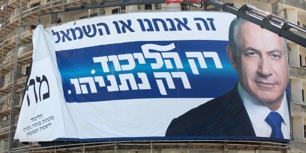 Workers hang on a building a giant campaign poster showing Israeli Prime Minister and Likud party's candidate running for general elections Benjamin Netanyahu on March 8, 2015 in the costal Israeli city of Tel Aviv. Tens of thousands of people rallied in Tel Aviv on March 7, 2015 against Netanyahu and called for 'change', 10 days ahead of a general election. AFP PHOTO / MENAHEM KAHANA (Photo credit should read MENAHEM KAHANA/AFP/Getty Images)