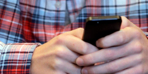 FILE - This Oct. 24, 2013 file photo shows a youth checking his smartphone in Glenview, Ill. Local police may be tracking you