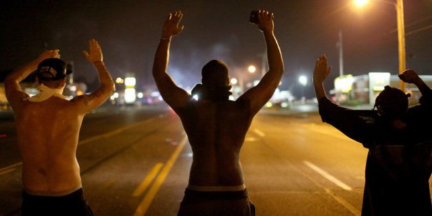 FERGUSON, MO - AUGUST 17: Demonstrators raise their arms and chant, 'Hands up, Don't Shoot', as police clear them from the street as they protest the shooting death of Michael Brown on August 17, 2014 in Ferguson, Missouri. Police sprayed pepper spray, shot smoke, gas and flash grenades as violent outbreaks have taken place in Ferguson since the shooting death of Michael Brown by a Ferguson police officer on August 9th. (Photo by Joe Raedle/Getty Images)