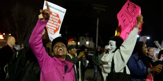 People demonstrate across the street from the Ferguson Police Department, Thursday, March 12, 2015, in Ferguson, Mo. Two police officers were shot early Thursday morning in front of the Ferguson Police Department during a protest following the resignation of the city's police chief in the wake of a U.S. Justice Department report. (AP Photo/Jeff Roberson)