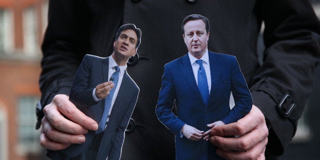 LONDON, ENGLAND - MARCH 18: A TV reporter holds cut out photographs of Prime Minister David Cameron and opposition Labour Party Leader Ed Miliband ahead of today's budget in Downing Street on March 18, 2015 in London, England. The Chancellor is presenting his 5th Budget to Members of Parliament today, the last before the General Election on May 7, 2015. (Photo by Peter Macdiarmid/Getty Images)